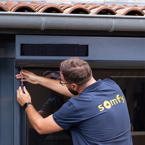 Technicien remplaçant un moteur Somfy dans un coffre de volet roulant à Strasbourg